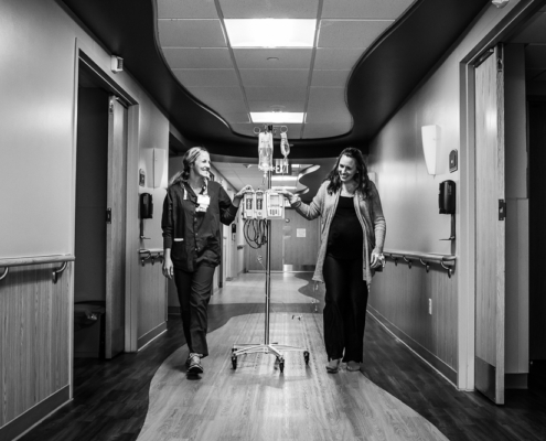 Woman in labor walking down hall with Madison Women's Health OBGYN providers