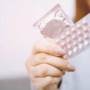 Woman's hand holding birth control pills and a condom