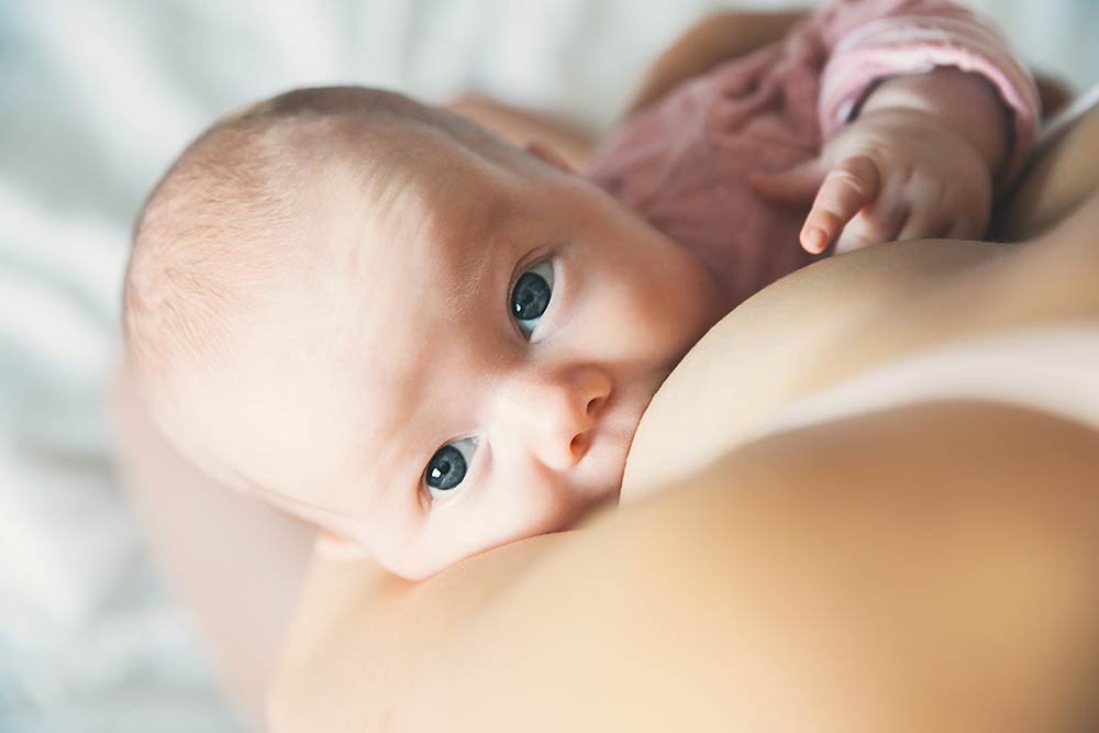 New mom breastfeeding her baby in bed