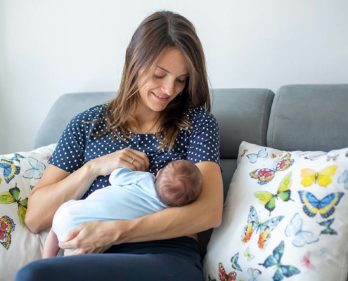 New mom breastfeeding her baby on a couch