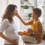 Boy feeds an orange to pregnant woman with gestational diabetes