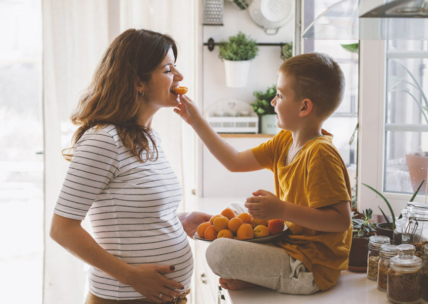 Boy feeds an orange to pregnant woman with gestational diabetes