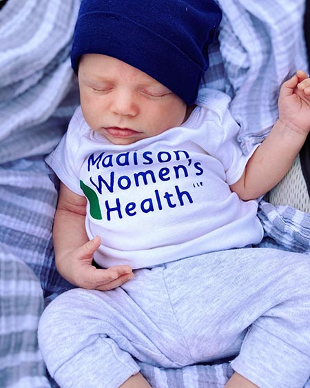 Adorable newborn baby wearing Madison Women's Health onesie