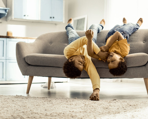 Boys lying across the couch upside down barefoot and laughing.