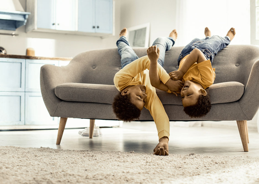 Boys lying across the couch upside down barefoot and laughing.